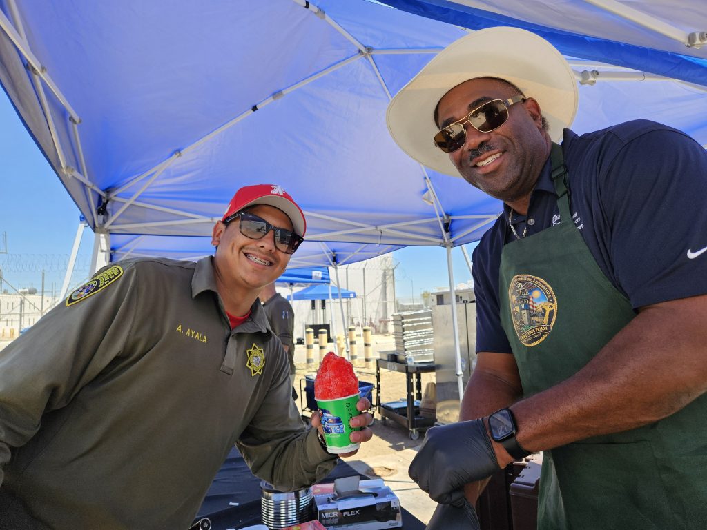 Two people smiling during an outdoor event at Centinela State Prison, May 2026.