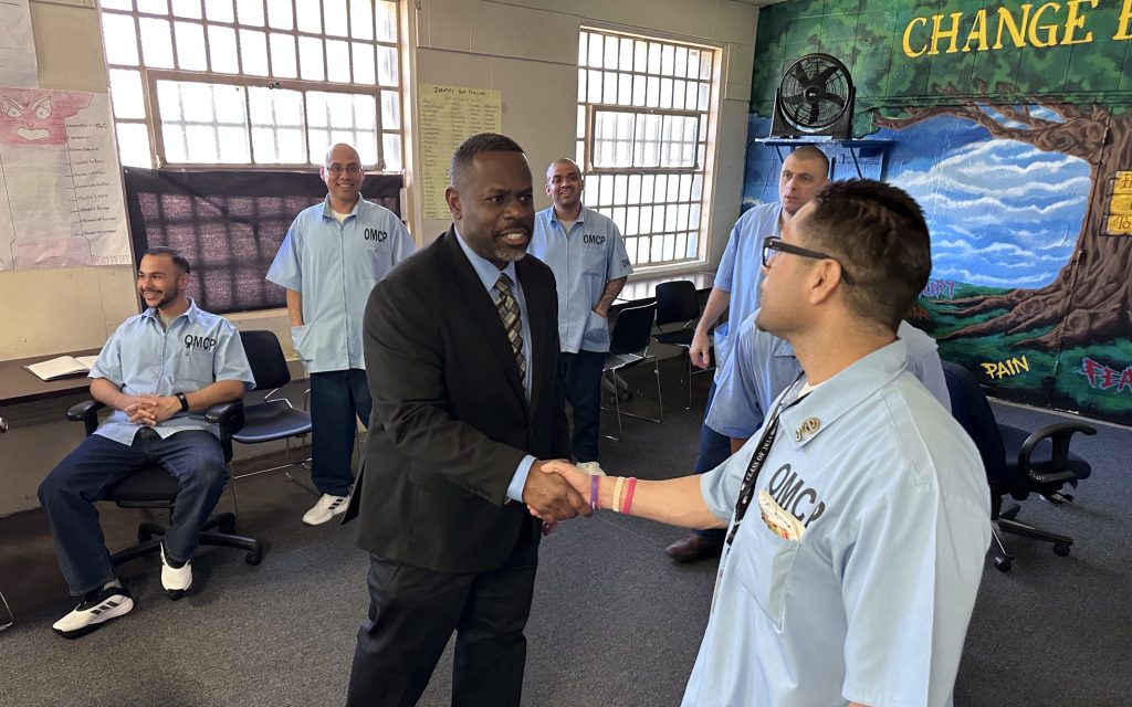 An incarcerated Occupational Mentor Certification Program member shakes hands with a CDCR Undersecretary at the Correctional Training Facility at Soledad.