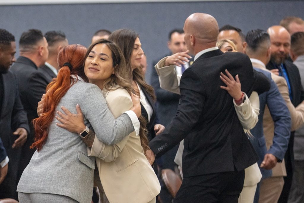Parole agents hug after the graduation ceremony.