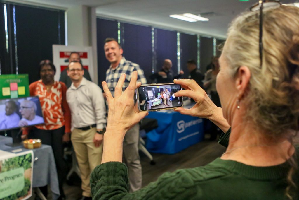 Woman takes photo on her phone of group of staff at 2026 CNE Conference