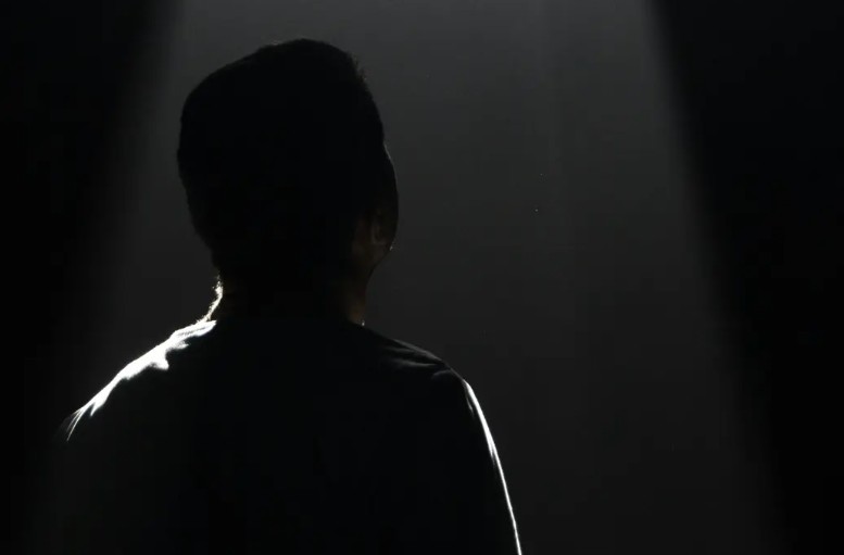 Incarcerated man looking up at window, black and white silhouette