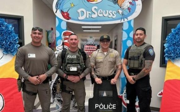 CDCR staff from LAC with another police officer to read to students during Read Across America Week, celebrating Dr. Seuss.