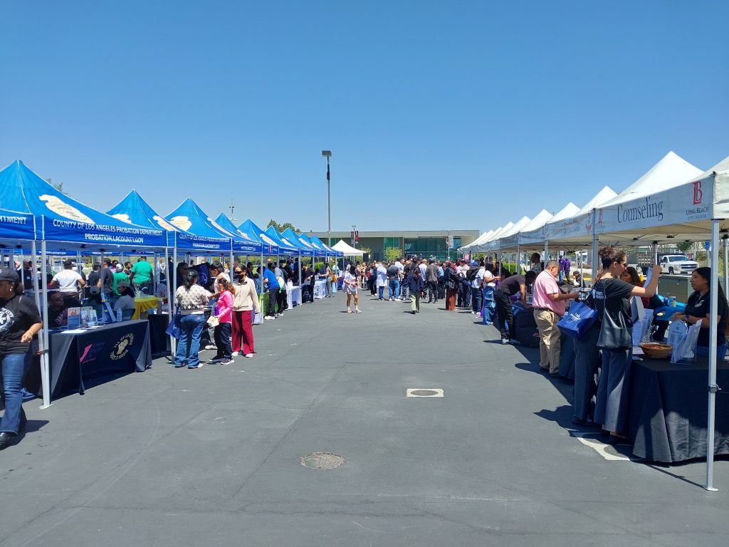 Outdoor reentry fair with many booths and people gathering and walking