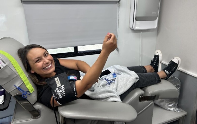 A smiling woman donates blood.
