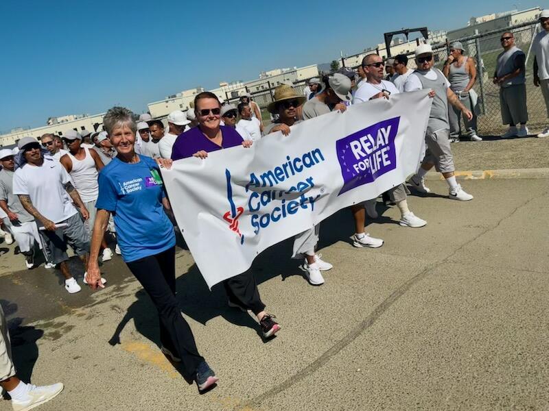 PVSP staff and incarcerated walk holding large American cancer society banner