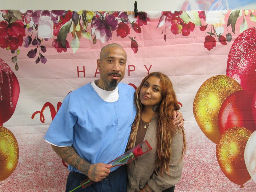 An incarcerated man presents a flower to a woman visiting during Mother's Day at California State Prison, Sacramento.