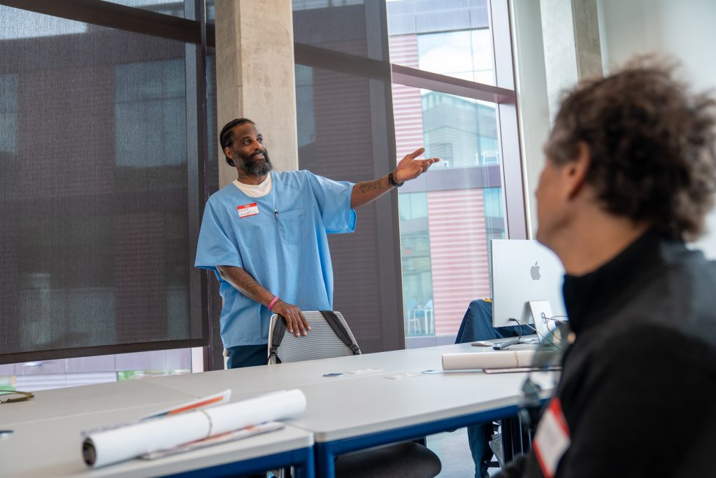 An incarcerated person shows off the new San Quentin Media Center, explaining the rehabilitative programs to be held in the new building.