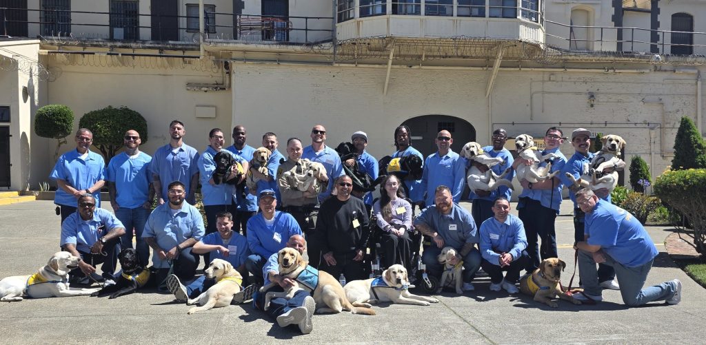 Puppy graduation at San Quentin group photo with visitors, staff and participants.