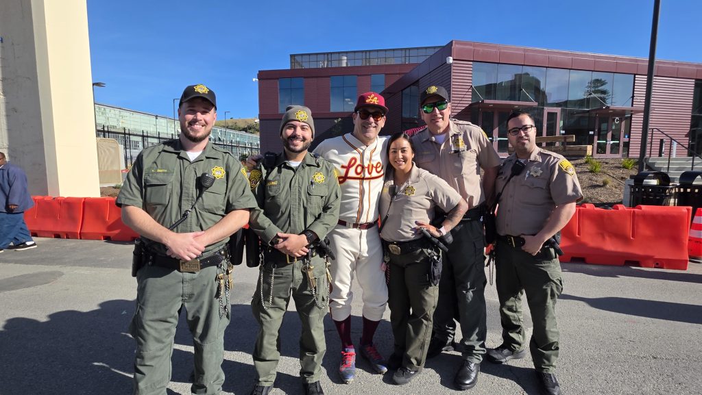 SQRC staff pose with actor John Hamm dressed in Love team baseball uniform