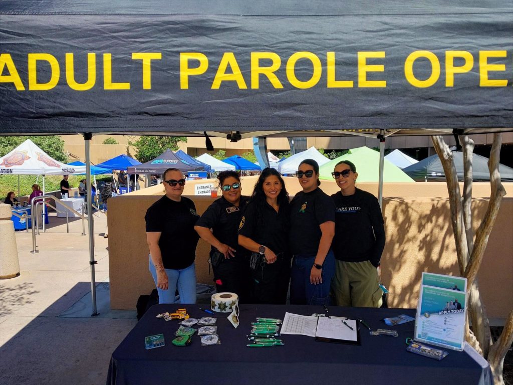 5 DAPO staff stand at outdoor resource booth at San Diego community resource fair