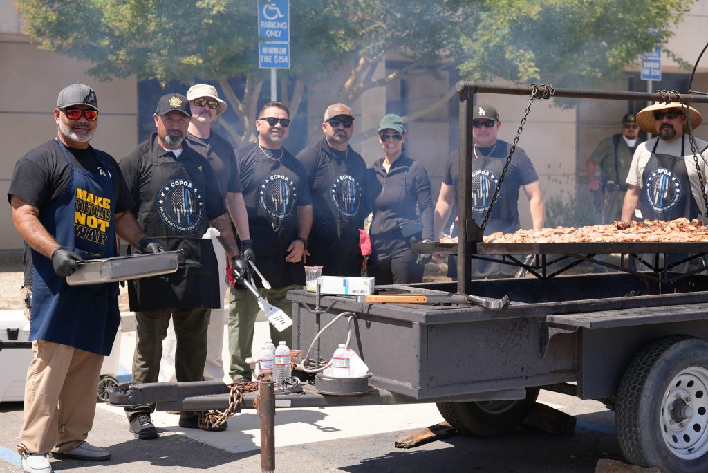 Group of people at a large outdoor grill at Valley S tate Prison. 