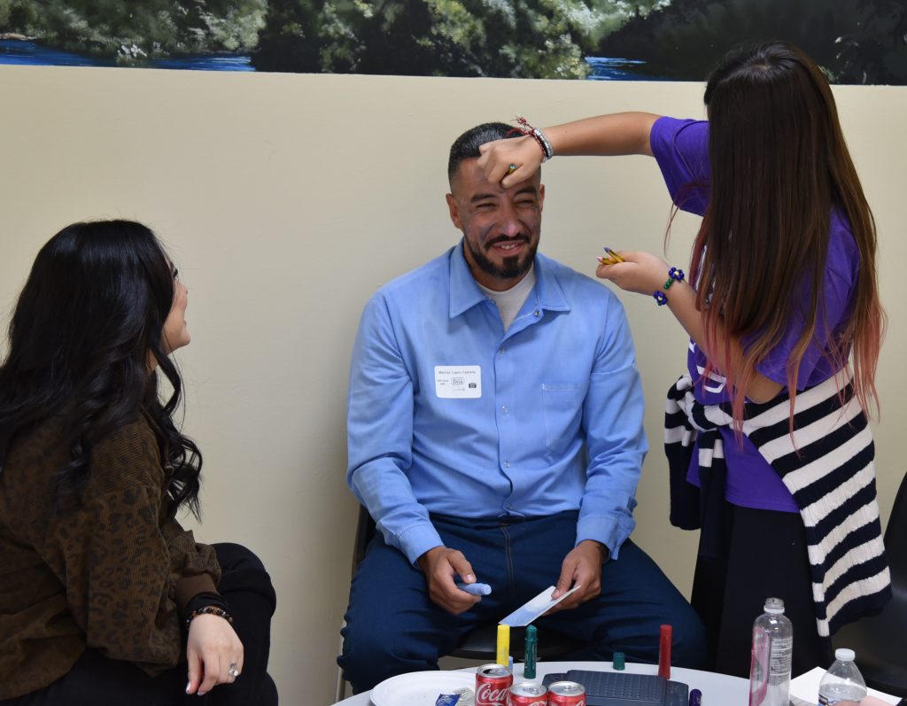 A child paints her incarcerated family member's face at Avenal State Prison.