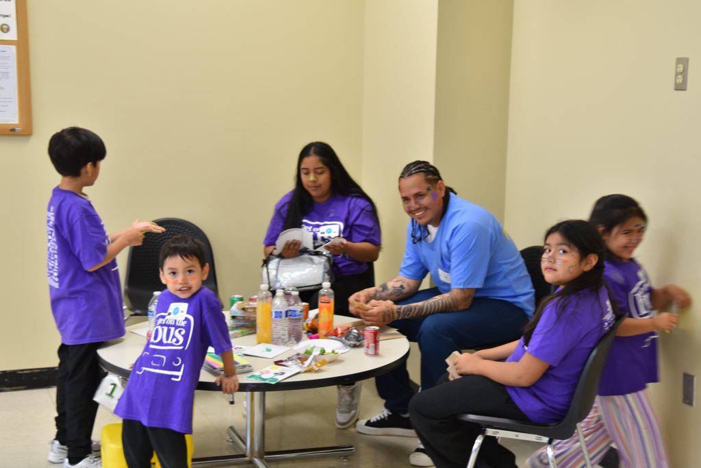 A family sits around a table at Avenal State Prison's visiting program with Get on the Bus. 