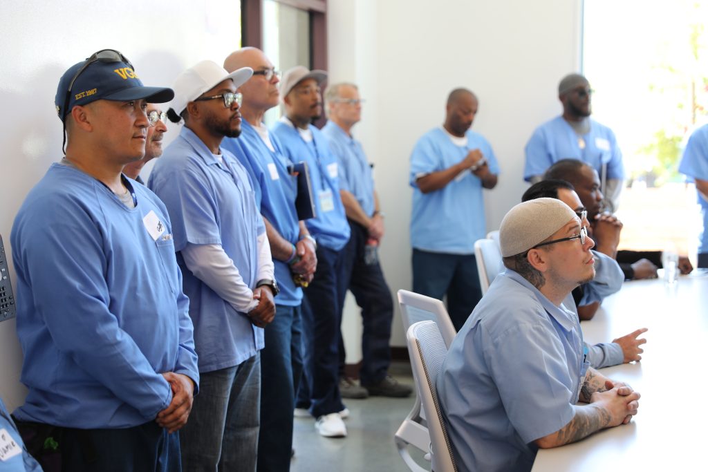Men wearing prison blues line the wall at The Last Mile coding program at San Quentin Rehabilitation Center, May 14, 2026.