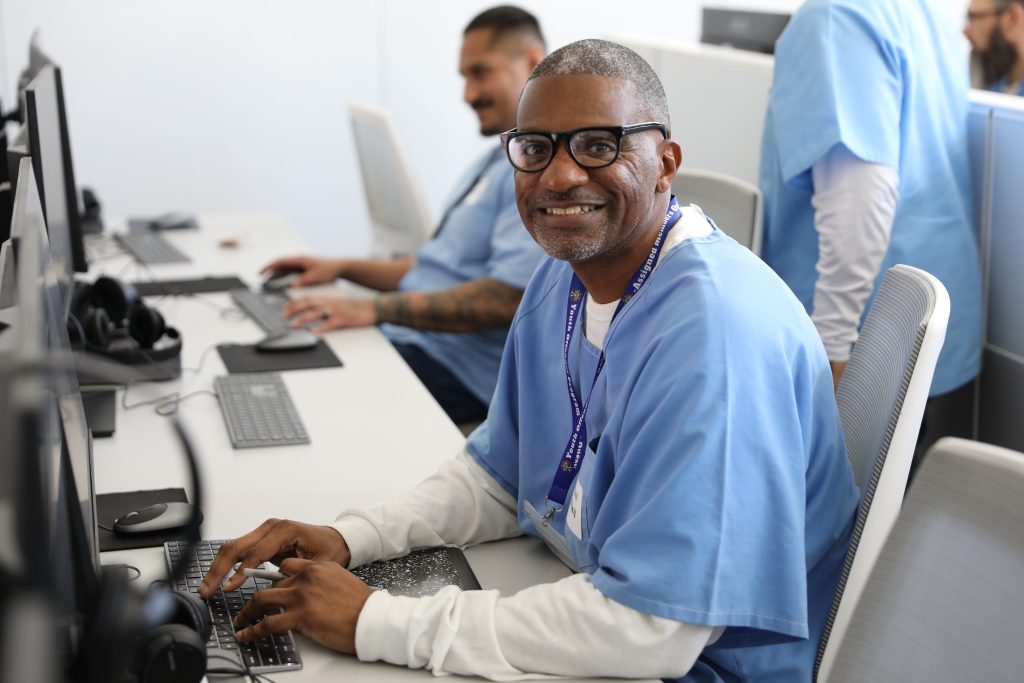 An incarcerated man sitting at a computer terminal learning coding as a job skill for when he is released from serving his sentence with the California Department of Corrections and Rehabilitation, or CDCR. He's shown as part of The Last Mile coding program offered at San Quentin Rehabilitation Center during a showcase for community partners and employers.