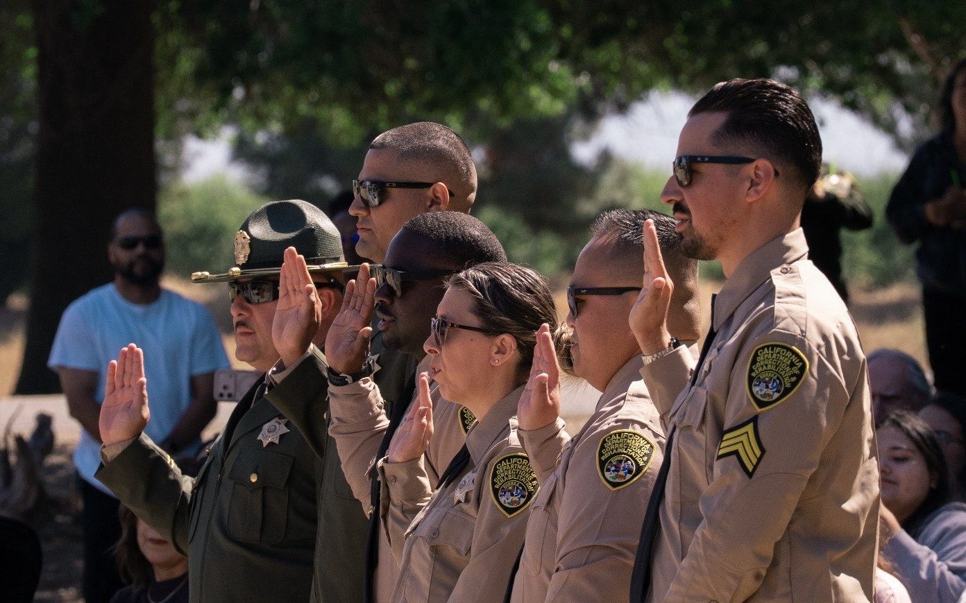 Recently promoted staff members raise their hands to take the oath of office at CCWF.