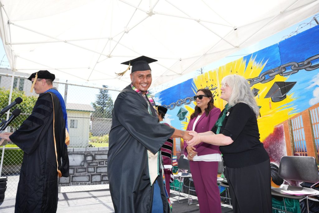Incarcerated student at graduation receiving college diploma