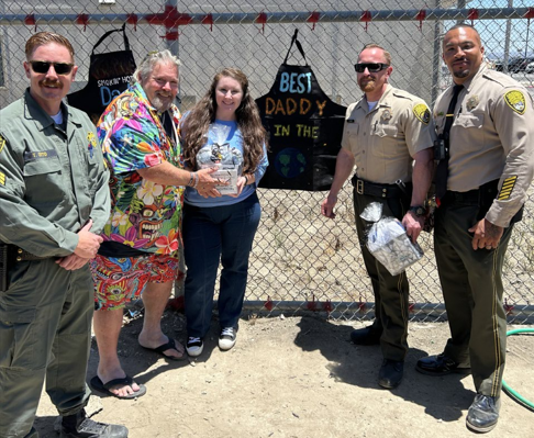 At California Institution for Women (CIW) in Corona, staff stand beside an incarcerated women who presents her dad with a gift during Father's Day visiting.