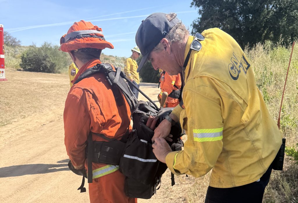 A Cal Fire trainer checks an incarcerated crew member's tool bag at CMC's annual fire training exercises with Cuesta Conservation Camp.