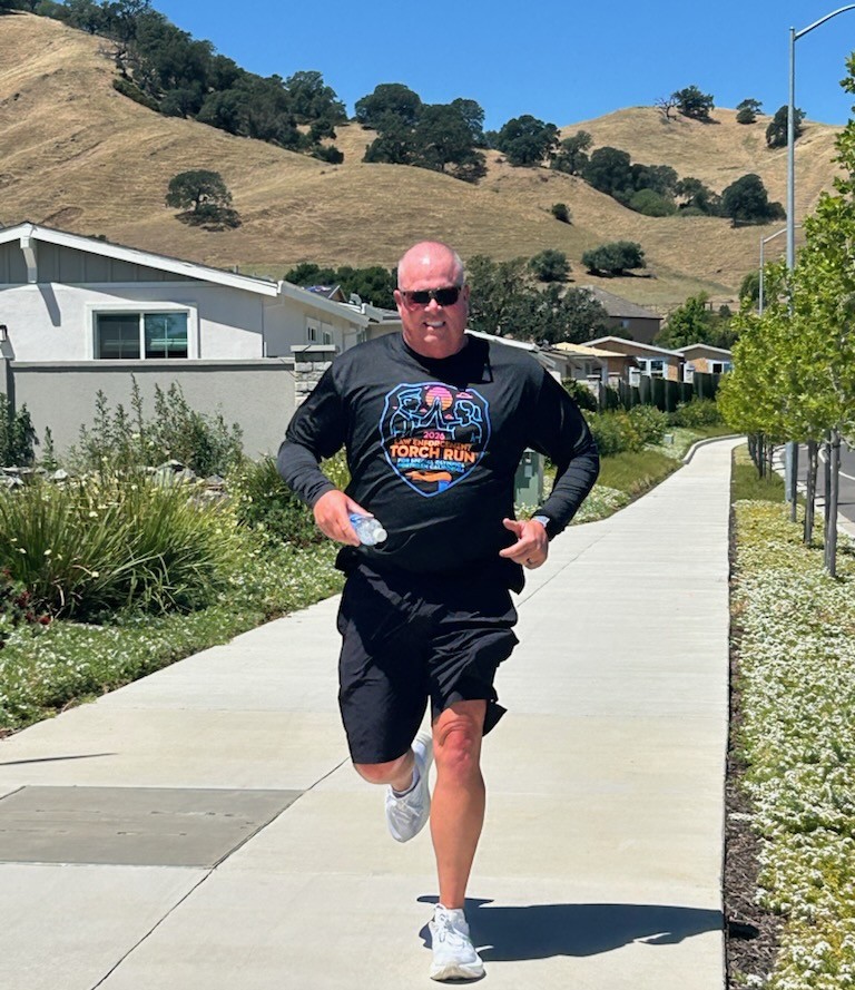 Man runs along sidewalk for CMF 2026 Torch Run.