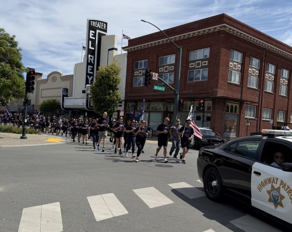 Runners pass by the El Rey theater during the Torch Run.