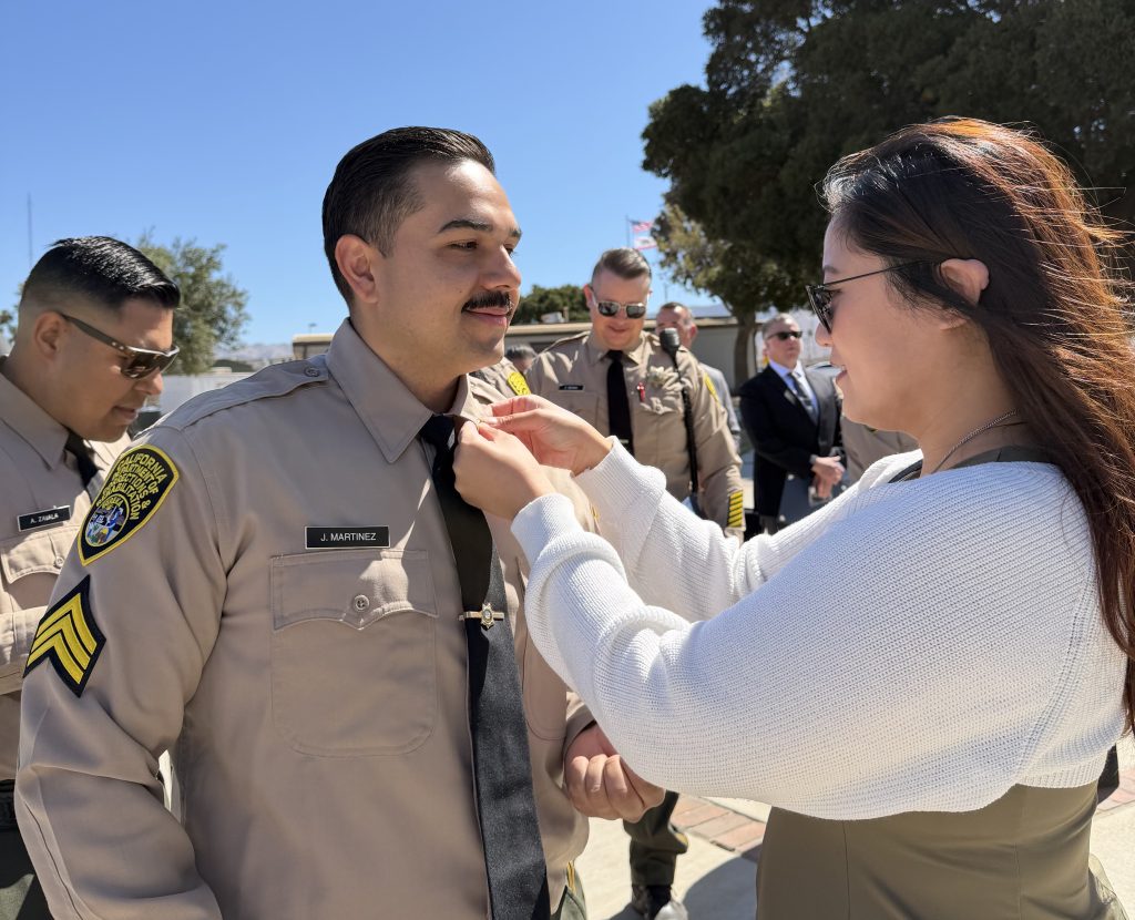 A woman pins the rank insignia on her promoted family member at CTF-Soledad.