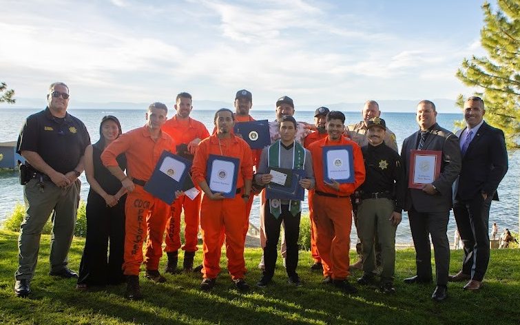 Group photo of incarcerated people and CDCR staff with Lake Tahoe in the background.