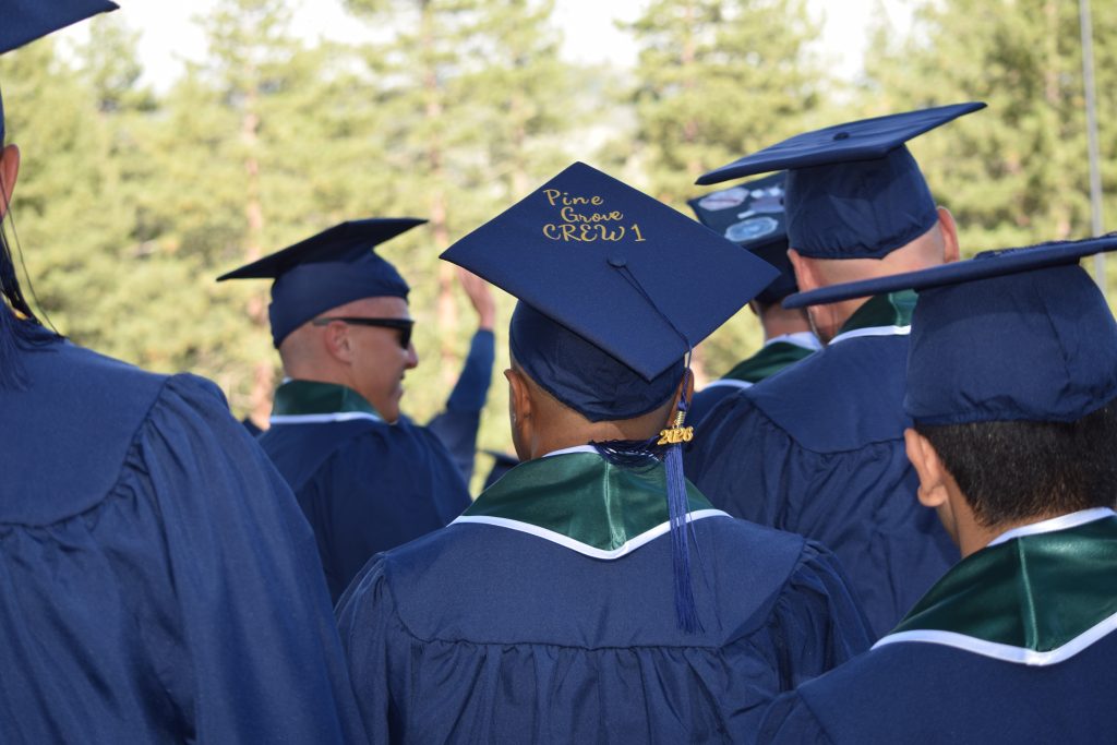 Graduates wearing caps and gowns with one cap featured the words Pine Grove.