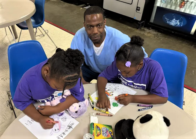 Ira Daniels and his granddaughters coloring at Correctional Training Facility in Soledad, California. 