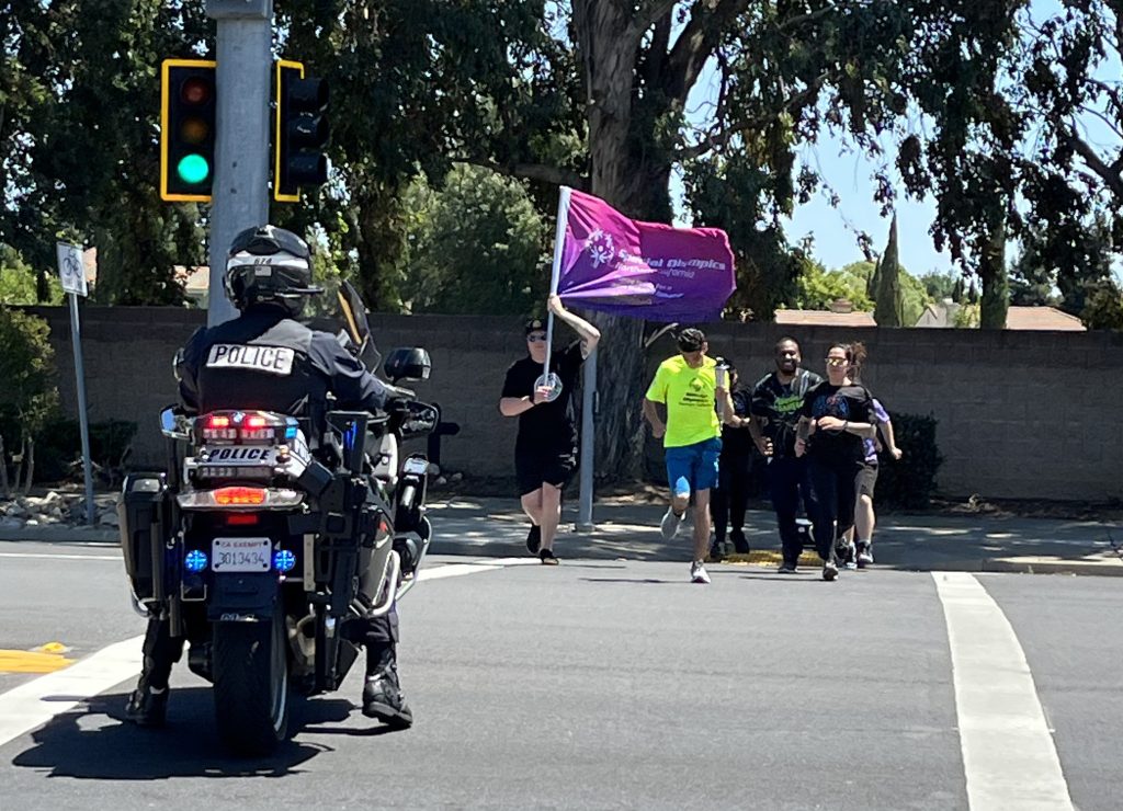 LETR runners cross the street with a police motorcycle escort.