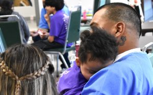 Salinas Valley State Prison's Get on the Bus event with a child sleeping on their loved one's shoulder.