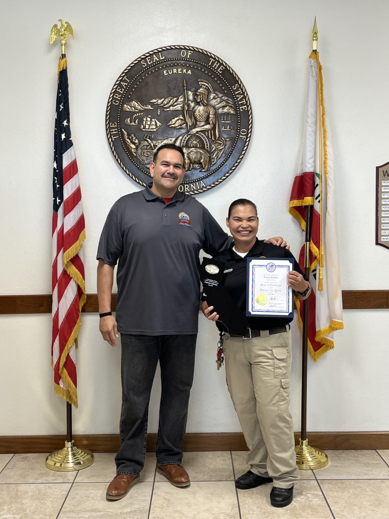 Staff member holds a certificate while another person stands beside her.