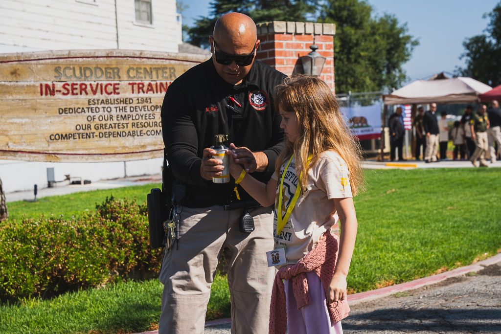 A correctional officer demonstrates gear to a young person at CIM.