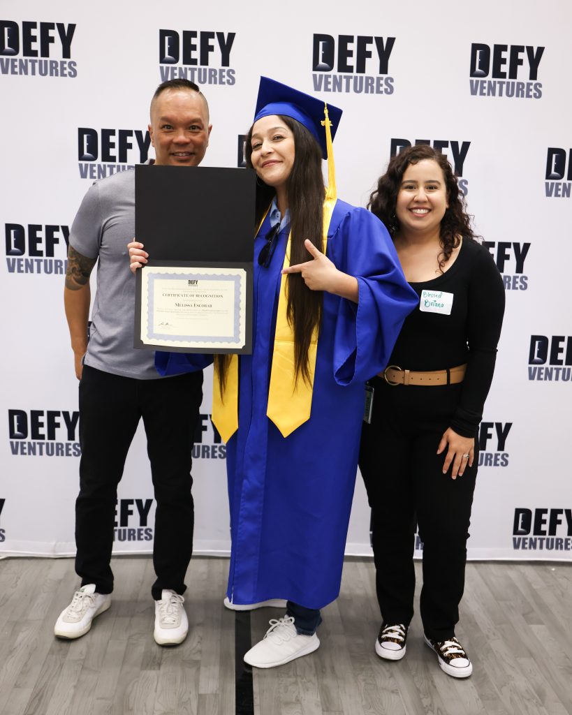 Graduate with two people from the Defy Ventures program at CIW.