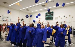 Graduates from the Defy Ventures program at California Institution for Women in Corona, or CIW, toss their caps in the air.