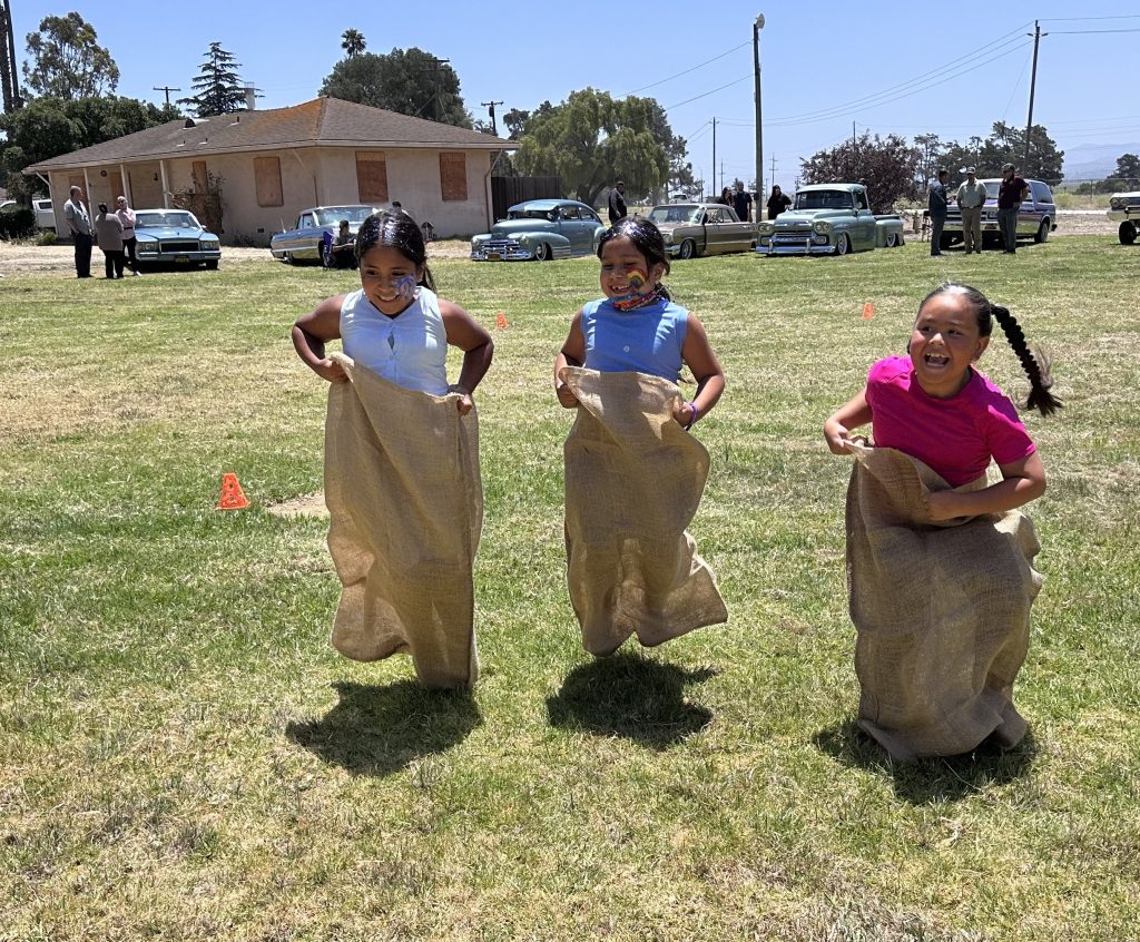 Three children in a potato sack race. 