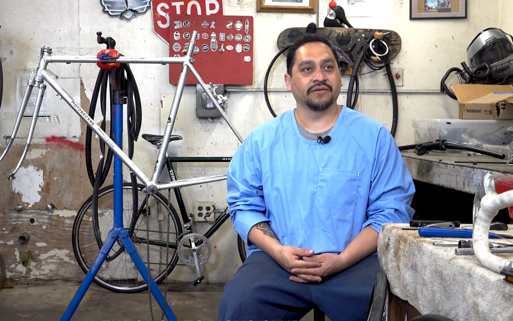 Sandoval, an incarcerated person, sits in the bike program shop at Folsom State Prison.