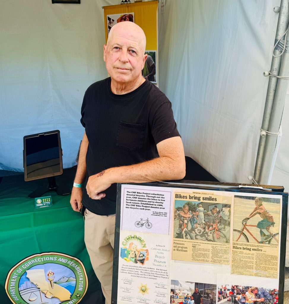 The person in charge of the bicycle refurbishment project at California Medical Facility in Vacaville with newspaper clippings about the program.