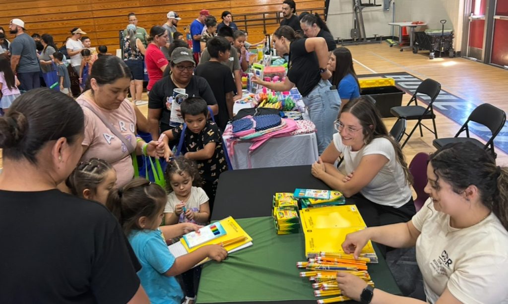 Avenal State Prison staff distribute school supplies and backpacks to families during a back-to-school event.