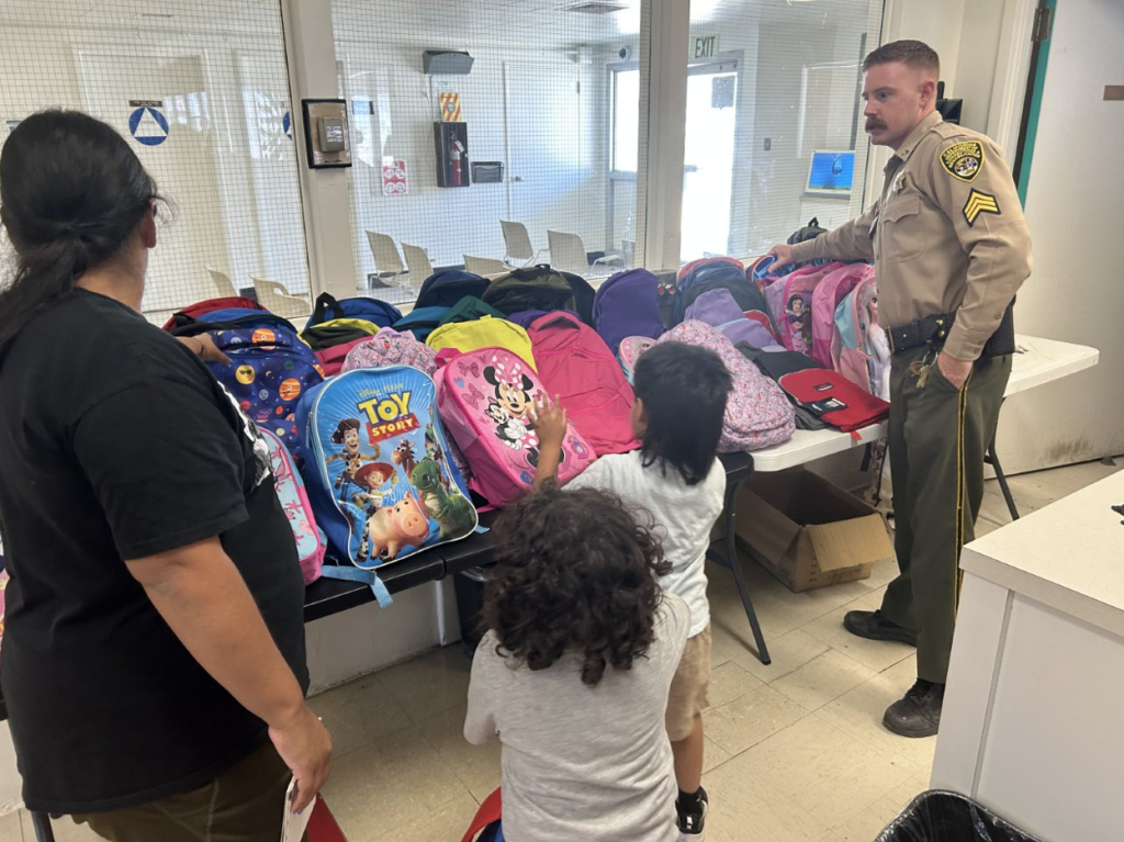 Staff, family, and backpacks at back-to-school event