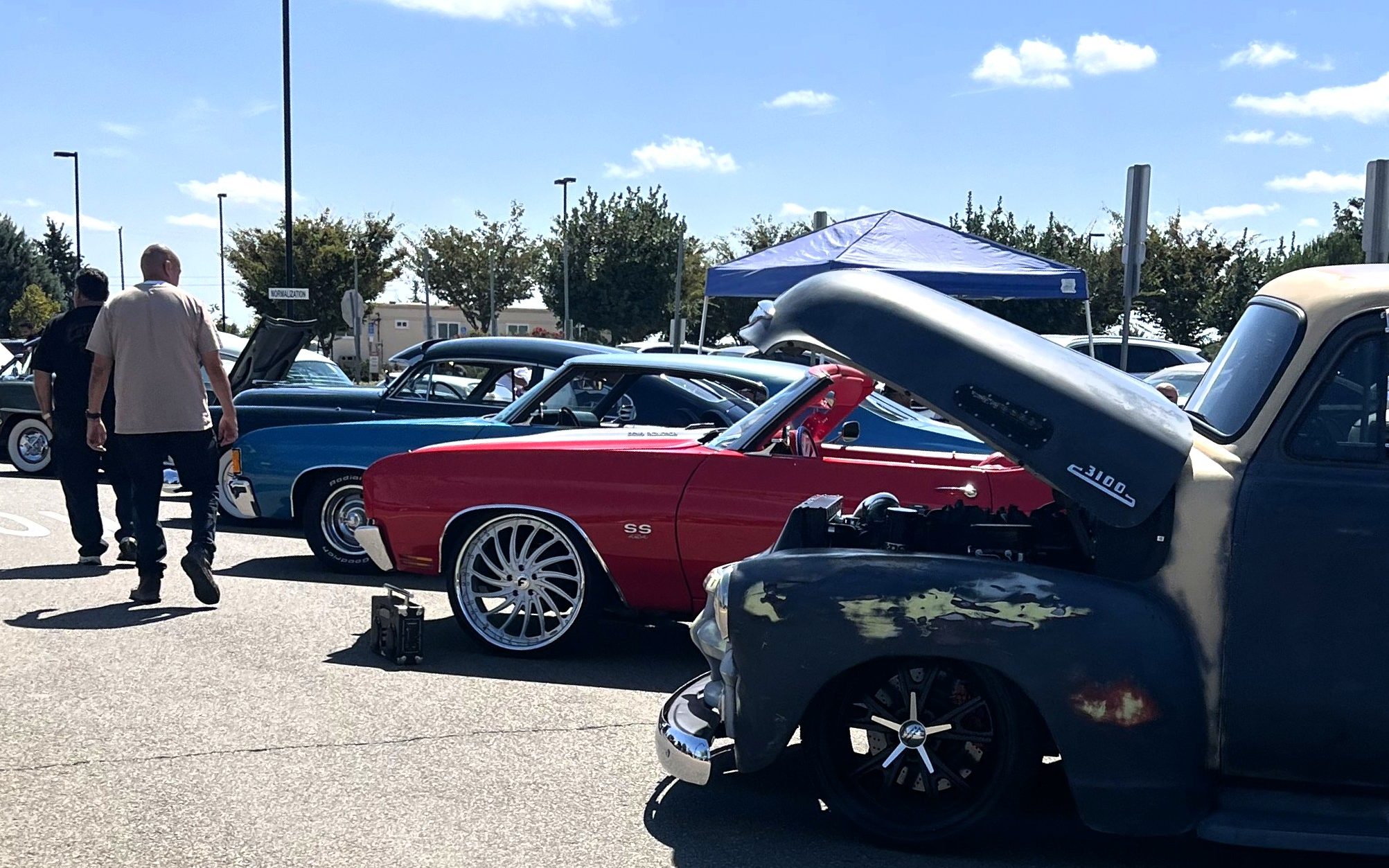 Two people walk along the automotive show at CHCF in Stockton.