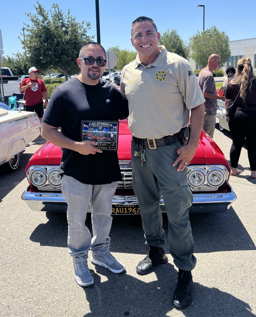 Automotive show at CHCF with two people, one holding an award.