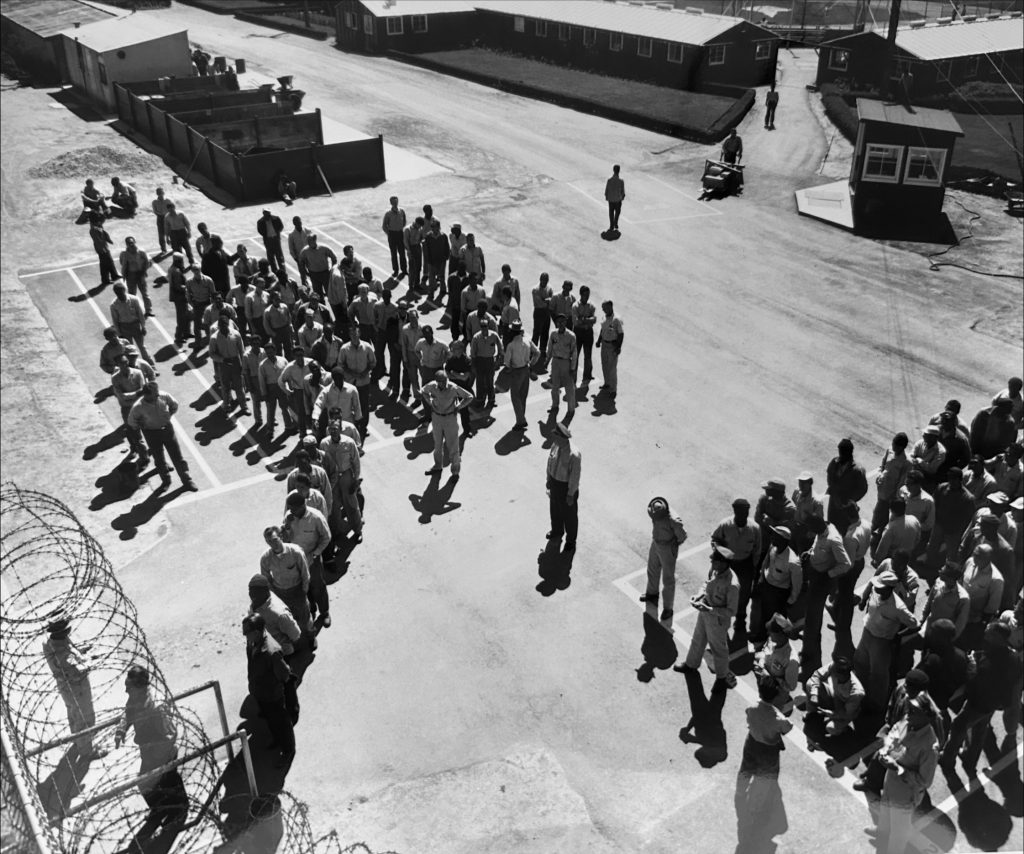 Incarcerated people and staff at CTF-Soledad, undated. The original Camp Barracks can be seen in the background.