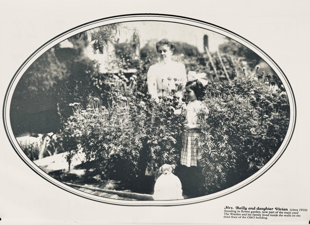 Mrs. Reilly and daughter Vivian in the flower garden, now part of the main yard at Folsom State Prison in 1910. The warden and his family lived on the third floor of the Officers and Guards building.
