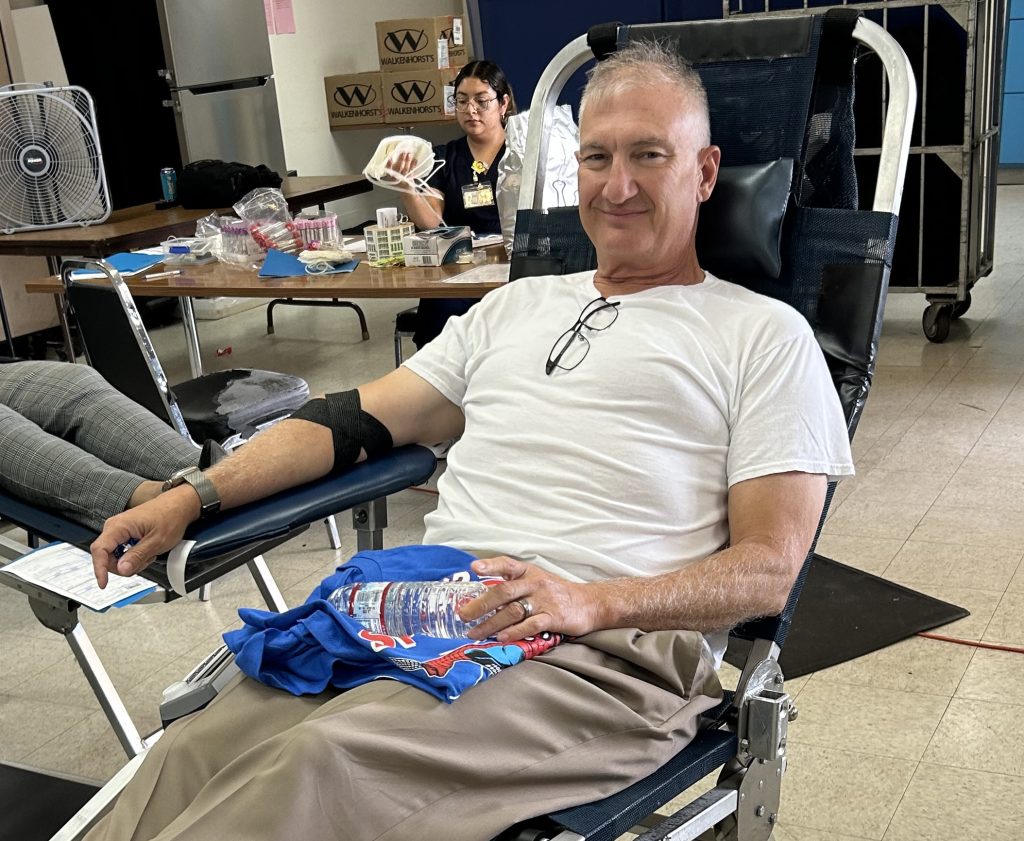 A man in a white shirt donates blood at RJD.