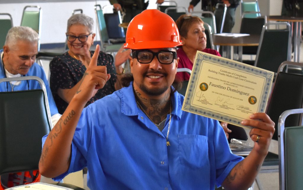 A graduate holds his certificate at SVSP.