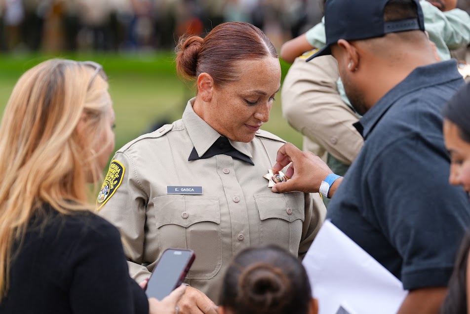 A family member pins the badge on a new correctional officer.