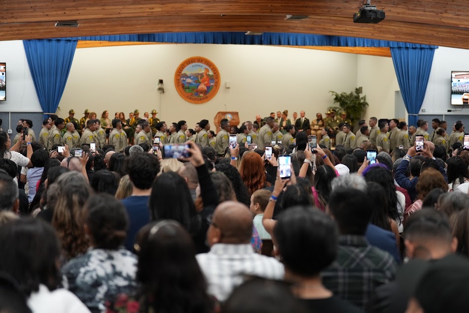 Basic Correctional Officer Academy Class 3-26A with family members in the audience capturing the moment on their cell phones.