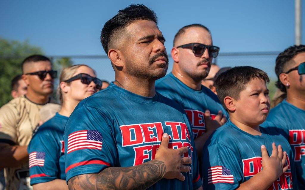 Staff and family members hold hands over hearts during the pledge of allegiance during opening ceremonies at the first Centinela State Prison Dodgeball Tournament.