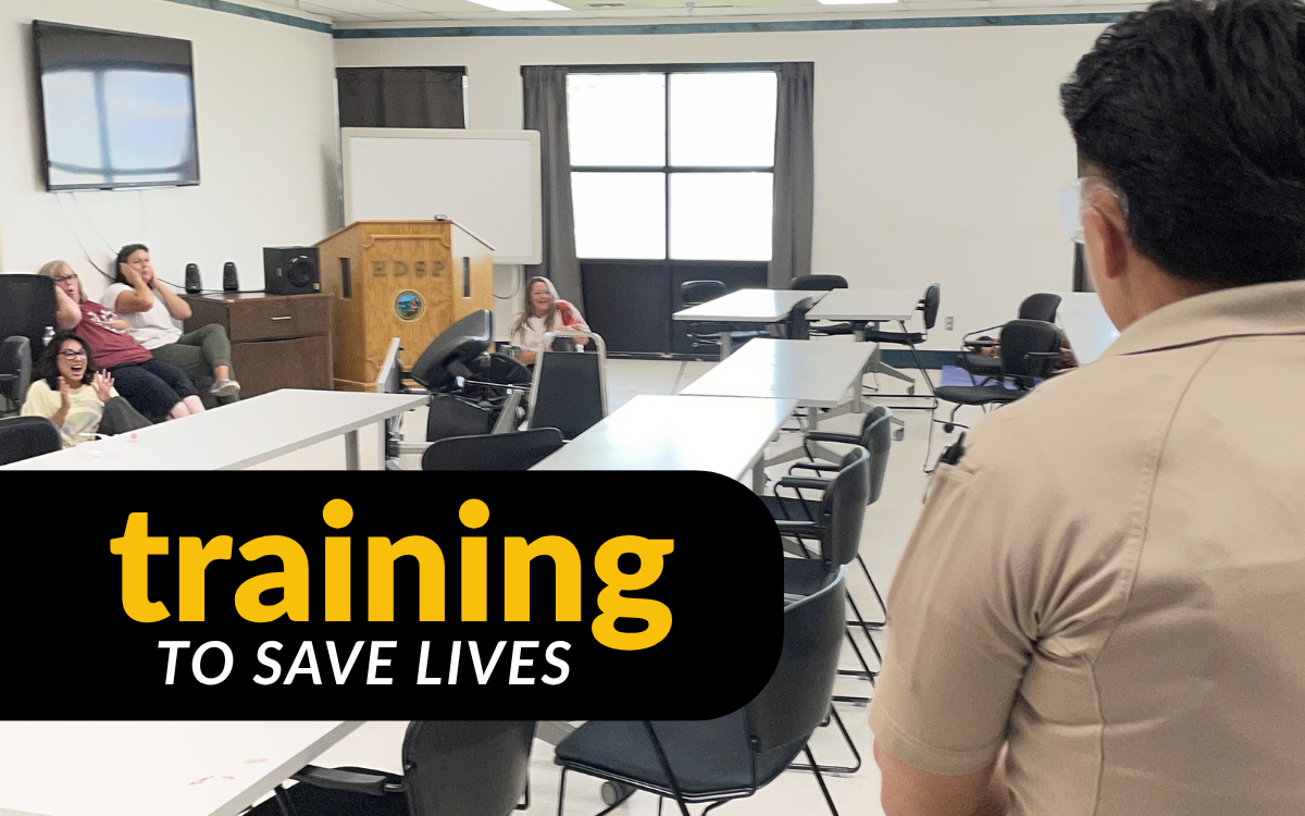 Staff hide in a corner behind a barricade during an active shooter mass casualty training exercise at High Desert State Prison (HDSP) in Susanville in 2026. Words overlaying the image are: "training to save lives."